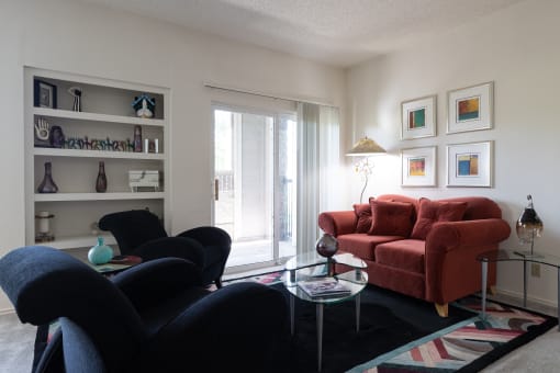 A one-bedroom living room at Hawthorne Apartment Homes featuring a navy blue sofa and a maroon loveseat, creating a cozy seating area.